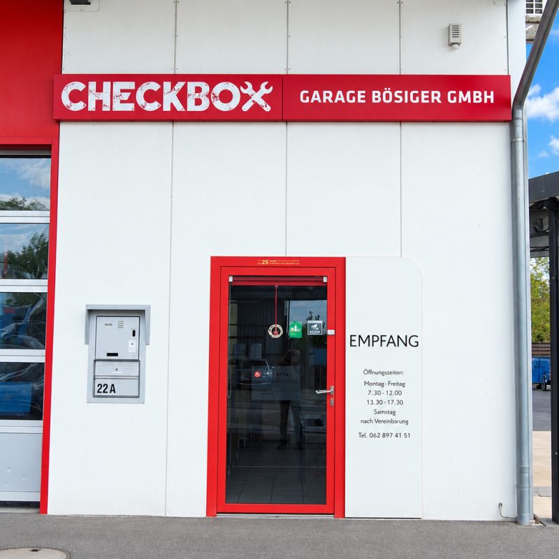 Rote Eingangstür zum Empfang der Garage Bösiger, neben der Hausnummer 22A.